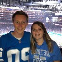 man and woman pose in front of football field